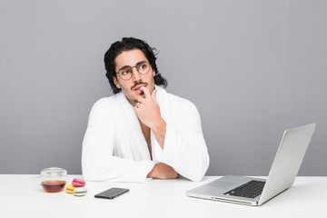 Young handsome man working after a shower relaxed thinking about something looking at a copy space.