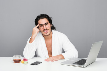 Young handsome man working after a shower showing a disappointment gesture with forefinger.