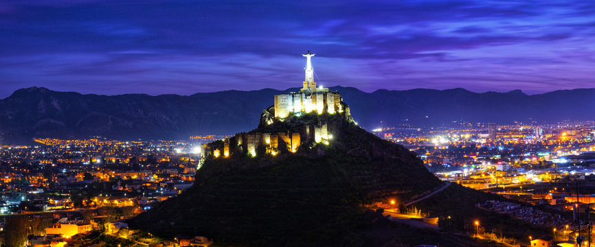 Panoramic view of Monteagudo Christ statue and castle at night in Murcia, Spain. Replica of the well-known Christ located on the top of the Concorvado Mountain in Rio de Janeiro.