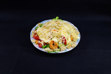 Caesar salad with shrimp on a black background.