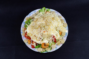 Caesar salad with shrimp close-up on a black background.