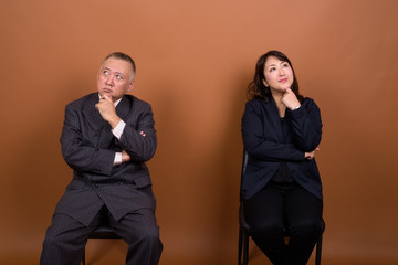 Mature Asian businessman and mature Asian businesswoman thinking together