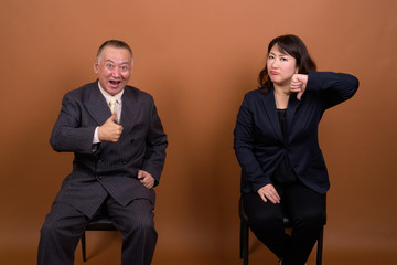 Mature Asian businessman and mature Asian businesswoman having different opinions together