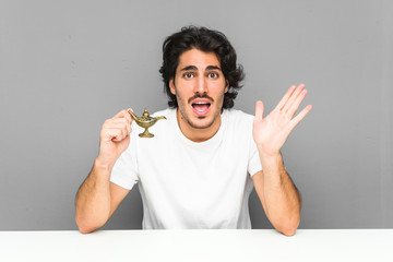 Young man holding a magic lamp celebrating a victory or success