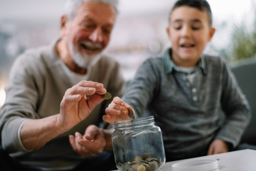 Grandpa and grandson saving money. Grandfather teaching grandchild how to save money.  