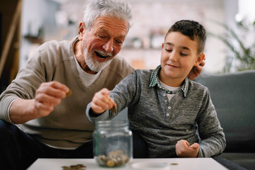 Grandpa and grandson saving money. Grandfather teaching grandchild how to save money.  
