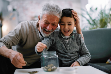 Grandpa and grandson saving money. Grandfather teaching grandchild how to save money.  