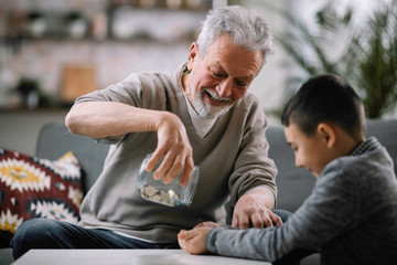 Grandpa and grandson saving money. Grandfather teaching grandchild how to save money.  