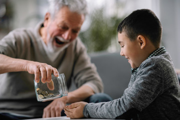 Grandpa and grandson saving money. Grandfather teaching grandchild how to save money.  