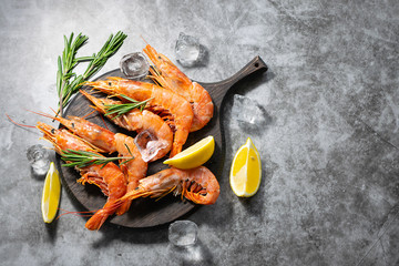 Flat lay overhead of fresh organic tiger shrimps or prawns on the wooden boars with rosemary, lemon...