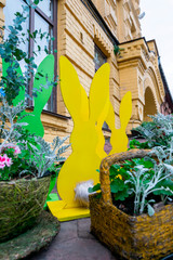 Wooden decorative Easter bunny yellow and green color located outdoor. Easter holiday concept background