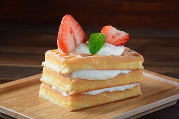 Belgian waffles with strawberries, whipped cream and mint leaves. Tasty dessert concept
