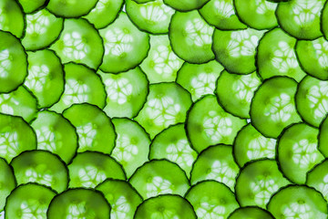 Textured background of multiple translucent overlapping backlit fresh green cucumber slices  © Helen Davies