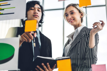 Group of casual business people planning and brainstorm writing over the project with stickers note on glass window at modern office.Teamwork concept