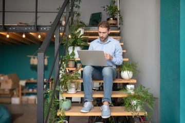 Fototapeta premium Man using a computer while sitting on stairs