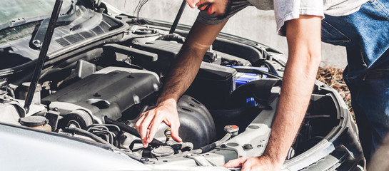 Professional car mechanic in uniform  fixing a car engine and repairing checking under the car hood...