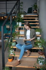 Woman wrking with a computer and paper documents on stairs