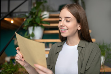 Smiling woman attentively reading a paper mail