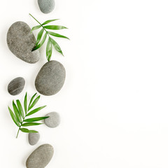 Obraz na płótnie Canvas Spa stones, palm leaves, candle and zen like grey stones on white background. Flat lay, top view