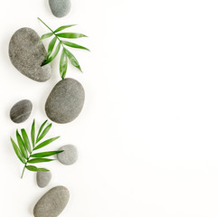 Spa stones, palm leaves, candle and zen like grey stones on white background. Flat lay, top view