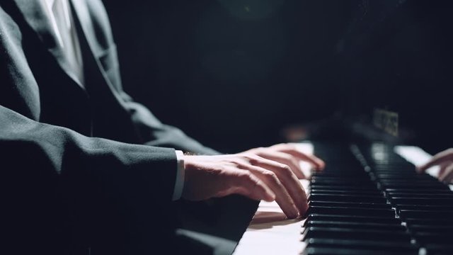Man two hands plays gentle classical music on a grand piano. Professional pianist