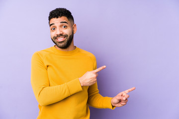 Young mixed race arabic man isolated shocked pointing with index fingers to a copy space.