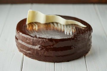 Dark chocolate vegan cake with candies and nuts on wooden background