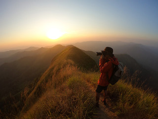 Male photographer taking photo on mountain at sunset
