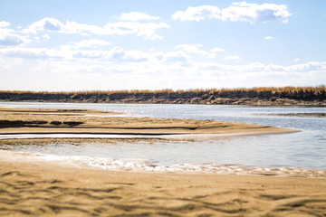 river bank with sand dunes with defocused shallow waters of river on the background