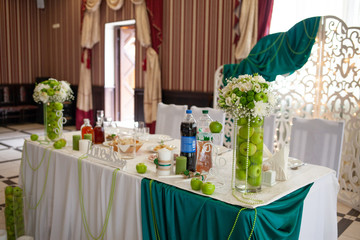 Beautiful green and white wedding decor of the bride and groom in a restaurant. Apple style in a restaurant. Apple decor