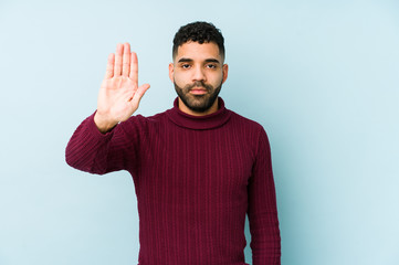 Young mixed race arabic man isolated standing with outstretched hand showing stop sign, preventing...