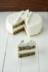 Birthday cake with white chocolate, butter cream and poppy seed biscuit on wooden background