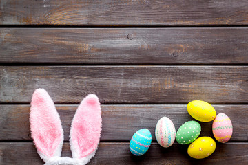 Easter concept. Eggs, bunny's ears on dark wooden background top-down copy space