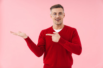 Portrait of handsome caucasian man pointing finger aside at copyspace