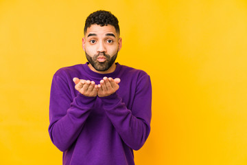 Young mixed race arabic man isolated folding lips and holding palms to send air kiss.