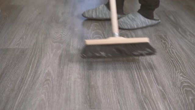 Mann fegt den Boden in der Wohnung