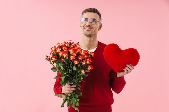 Portrait of handsome caucasian man holding flowers and toy heart