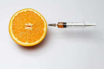 orange and syringe in it , gmo concept