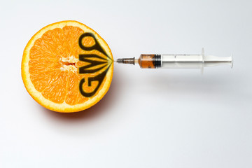 orange and syringe in it, gmo concept - obrazy, fototapety, plakaty