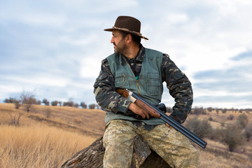 Hunter man in camouflage with a gun during the hunt in search of wild birds or game. Autumn hunting season.