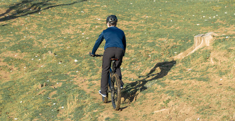 Plakat Cyclist in pants and fleece jacket on a modern carbon hardtail bike with an air suspension fork. The guy on the top of the hill rides a bike.