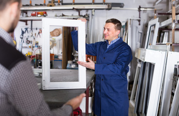 Production worker in coverall demonstrating different PVC windows to customer