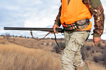 Hunter man in camouflage with a gun during the hunt in search of wild birds or game. Autumn hunting...
