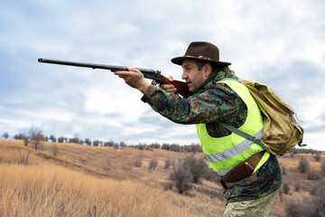 Hunter man in camouflage with a gun during the hunt in search of wild birds or game. Autumn hunting...