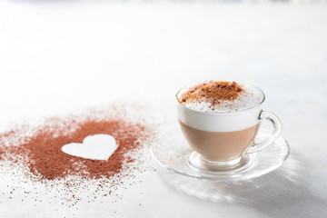 Cappuccino and heart made of cocoa powder on white background. The idea for a festive breakfast, Valentine's Day.