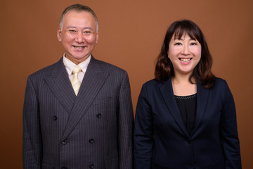 Happy mature Asian businessman and mature Asian businesswoman smiling together