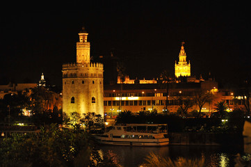 Fototapeta na wymiar Cityscape of Seville by night with the Torre del Oro (Golden Tower), the Giralda tower and Guadalquivir river, Andalusia, Spain