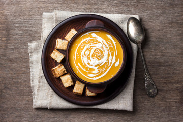 Pumpkin soup with cream and sesame seeds with croutons on wooden background