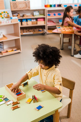 Selective focus of kid playing game with children at background in montessori school