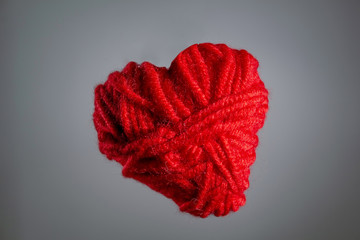 red heart made of knitted thread, valentines day. copy space. on a gray background